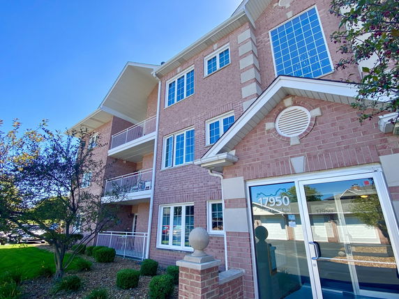 Front view of a multi-story brick apartment building with balconies.
