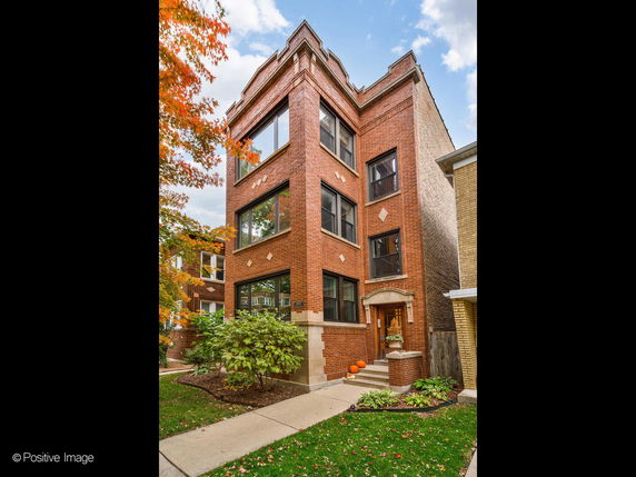 Front view of a multi-story brick building with large windows.