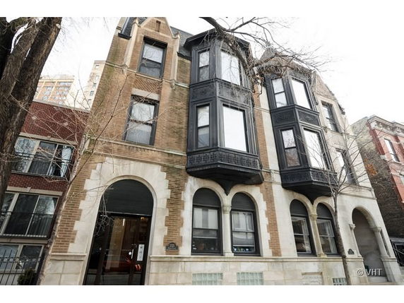 Front view of a multi-story building with arched windows and bay windows.