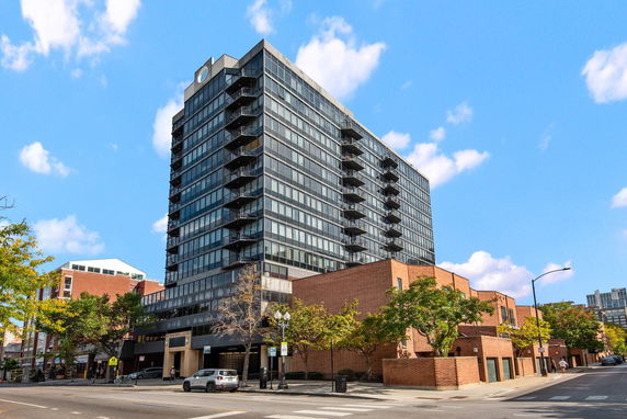 Front view of a multi-story glass apartment building with balconies.