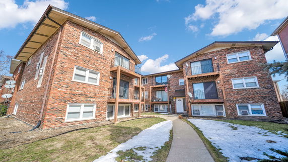 Front view of a multi-story brick apartment building with balconies.