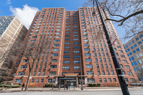 Front view of a high-rise apartment building with multiple floors and a central entrance.