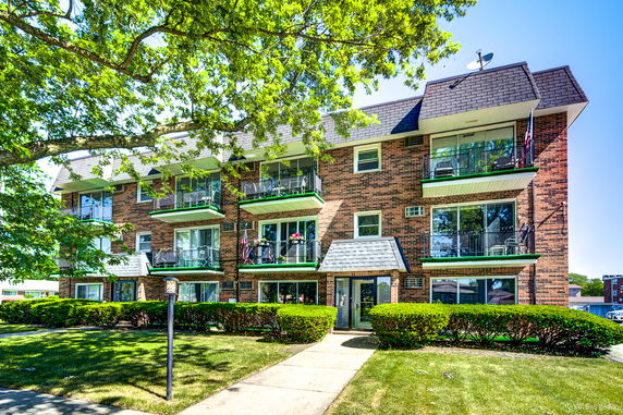 Front view of a multi-story brick apartment building with balconies.
