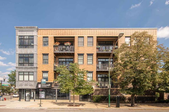 Front view of a multi-story brick apartment building with balconies.