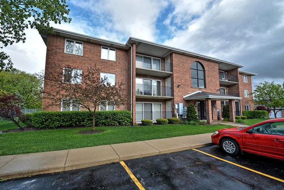 Front view of a three-story brick apartment building with balconies.