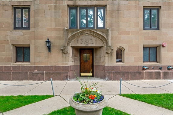 Front view of a building entrance with decorative arch and windows.