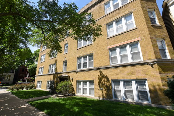 Front view of a multi-story brick building with several windows.