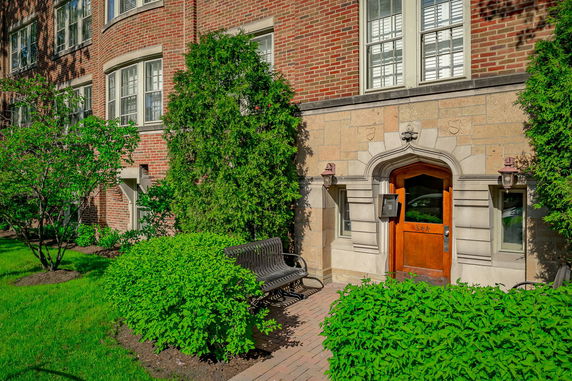 Front view of a brick building with an arched entrance and greenery.