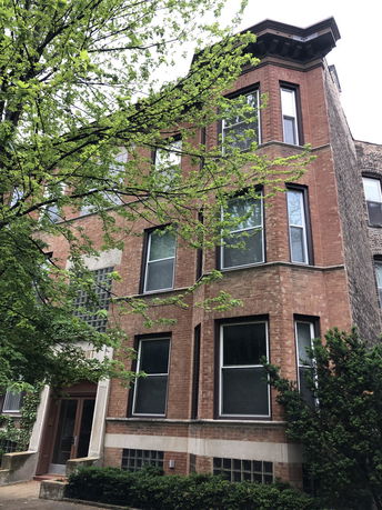 Front view of a multi-story brick building with large windows.
