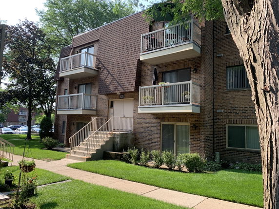 Front view of a multi-story brick apartment building with balconies and a staircase.