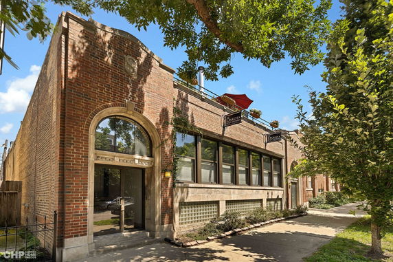 Front view of a brick building with large arched windows and a sign reading 'Dakota Lofts'.