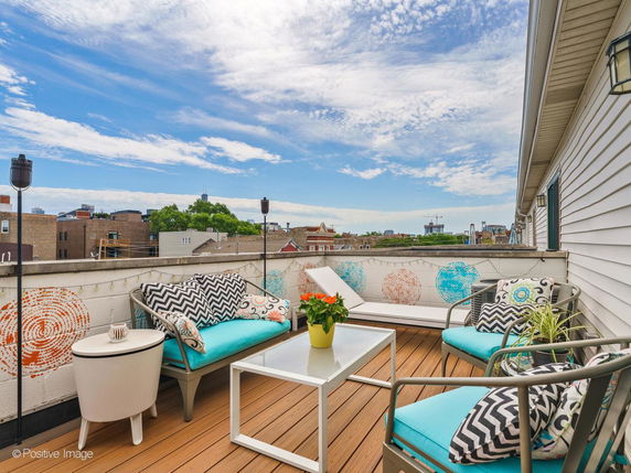 Rooftop seating area with colorful cushions and city view in the background.