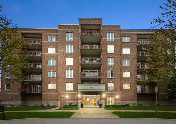 Front view of a multi-story brick apartment building with balconies.
