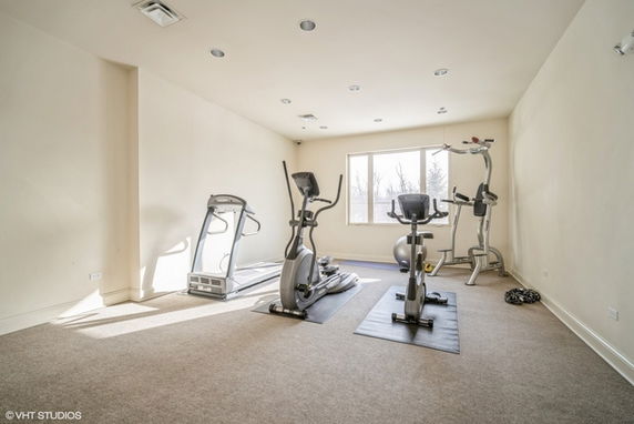 Room with exercise equipment including elliptical machines and stationary bike.