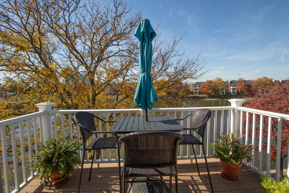 View of a deck with outdoor furniture and a scenic backdrop of water and trees.
