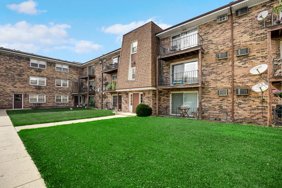 Front view of a multi-story brick apartment building with balconies.