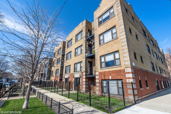 Front view of a multi-story apartment building with beige brick and red brick lower section.