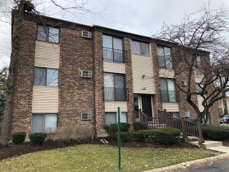 Front view of a multi-story brick apartment building with balconies and a central entrance.