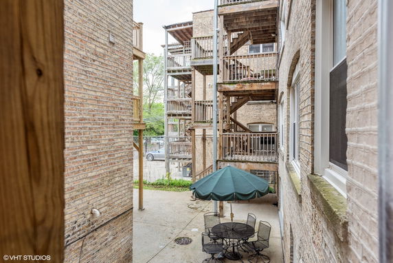 View of outdoor area between brick buildings with wooden staircases and a patio table with an umbrella.