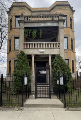 Front view of a multi-story house with a balcony and gated entrance.