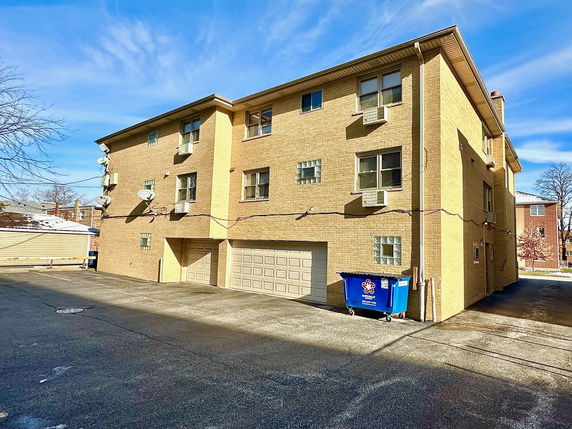 Front view of a multi-story brick building with garage and satellite dishes.