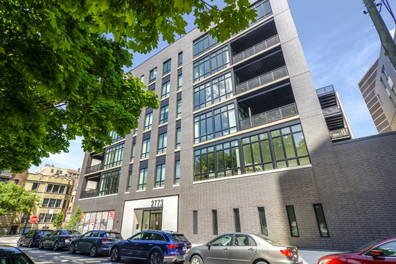 Front view of a modern multi-story building with large windows and multiple balconies.