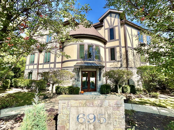 Front view of a multi-story house with large windows and stone accents.