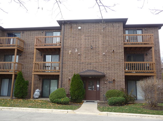 Front view of a brick apartment building with balconies.