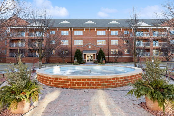 Front view of a multi-story brick building with a central entrance and balconies.