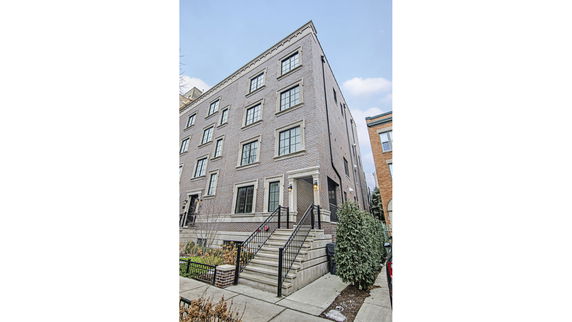 Front view of a multi-story brick building with stairs leading to the entrance.