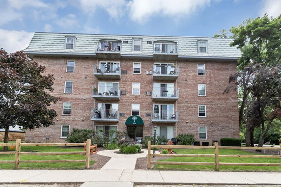 Front view of a multi-story brick apartment building with balconies.