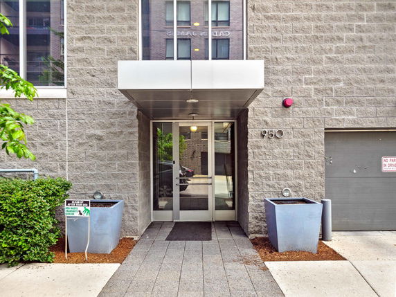 Main entrance of a modern building with a metal canopy and planters.