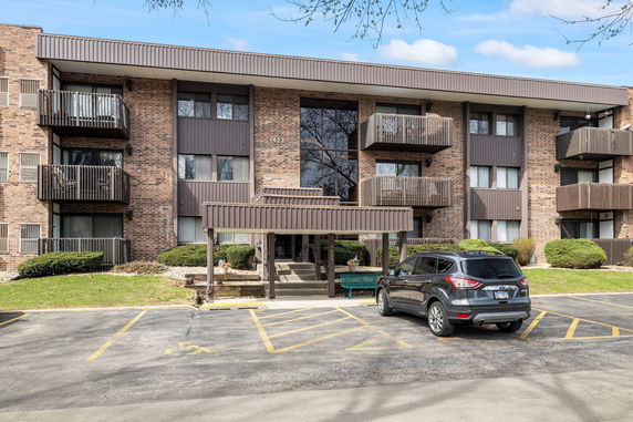 Front view of a multi-story brick apartment building with balconies.