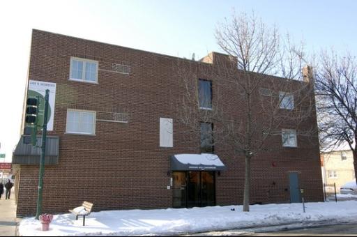 Front view of a three-story brick building with multiple windows and an entrance canopy.