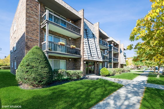 Front view of a three-story brick apartment building with balconies.
