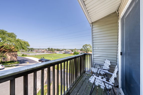 View from a balcony overlooking a grassy area and tennis courts.