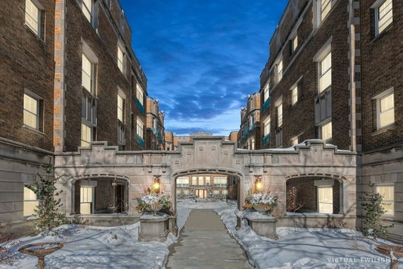 Front view of a multi-story brick building with an arched walkway and decorative stone elements.