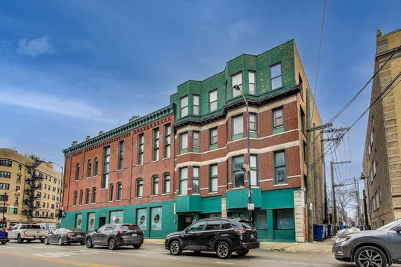 Front view of a multi-story brick building on a street corner.