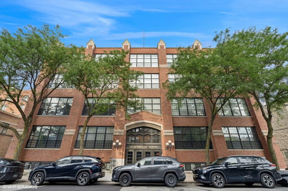 Front view of a multi-story brick building with large windows and a central entrance.
