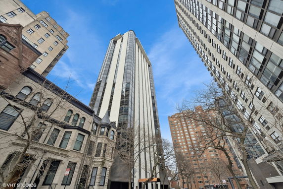 Street view of tall apartment buildings with some trees in the foreground.