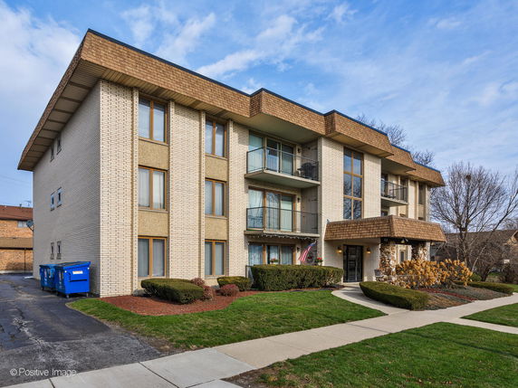 Front view of a three-story apartment building with a covered entrance.