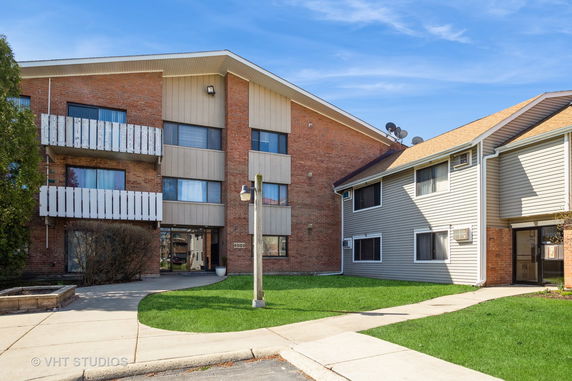 Front view of a building with brick and siding exterior and multiple balconies.