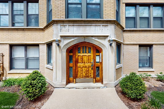 Front view of a brick residential building with a wooden arched doorway.
