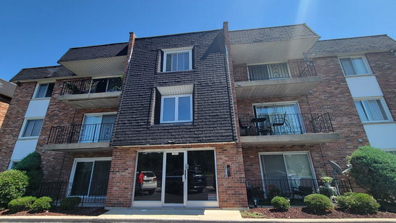 Front view of a multi-story brick apartment building with balconies.