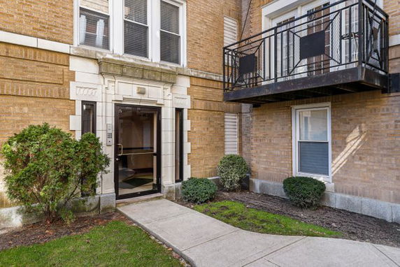Front view of a brick apartment building with a balcony.