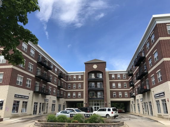 Front view of a four-story brick apartment building with balconies.