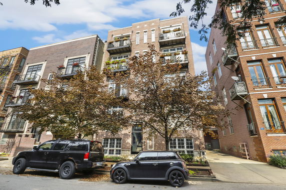 Front view of a multi-story brick apartment building with balconies.