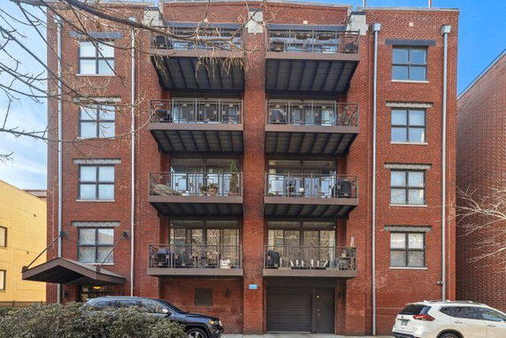 Front view of a multi-story red brick apartment building with balconies.