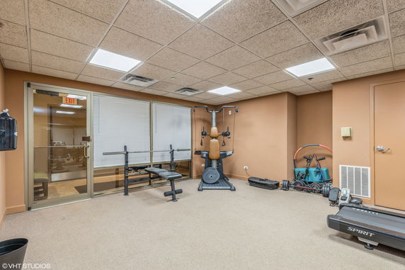 Indoor gym area with fitness equipment and a glass door.