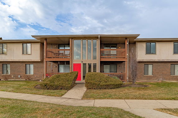 Front view of a two-story building with red doors and wooden balconies.